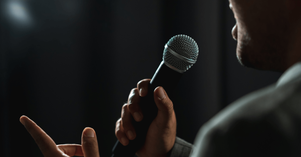 Person talking while holding a microphone.