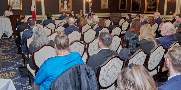 Many people sitting in chairs attending the RIBO Annual General Meeting and looking at a person speaking at a podium.